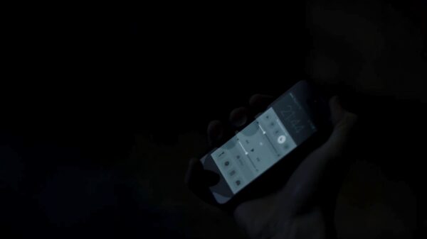 Tmavý obrázek s rukou držící telefon, na kterém je zapnutý noční režim.