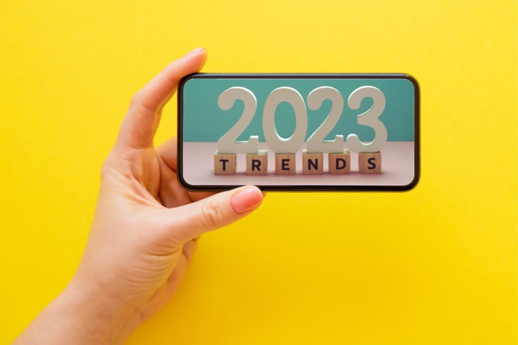 Ruka držící mobilní telefon s nápisem 2023 Trends.
